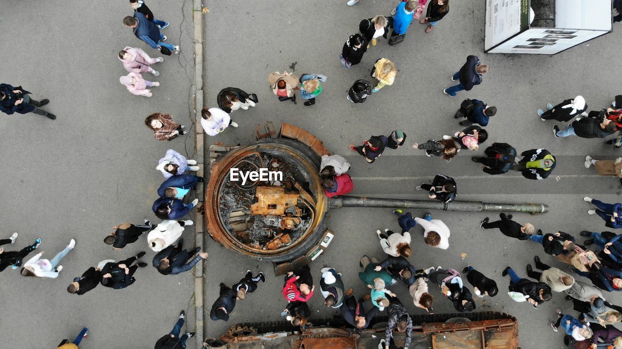 High angle view of people walking on street next to the wrecked russian fascist equipment