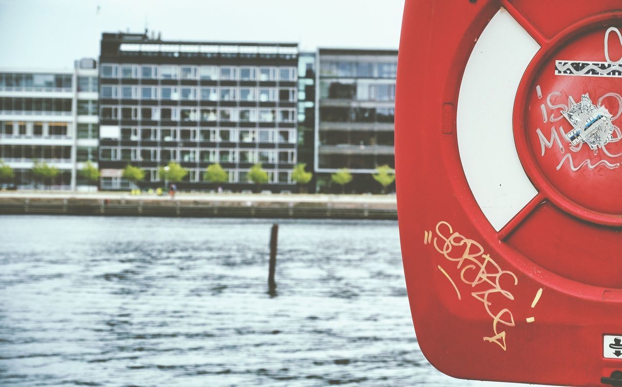 Cropped image of life belt container on beach against building