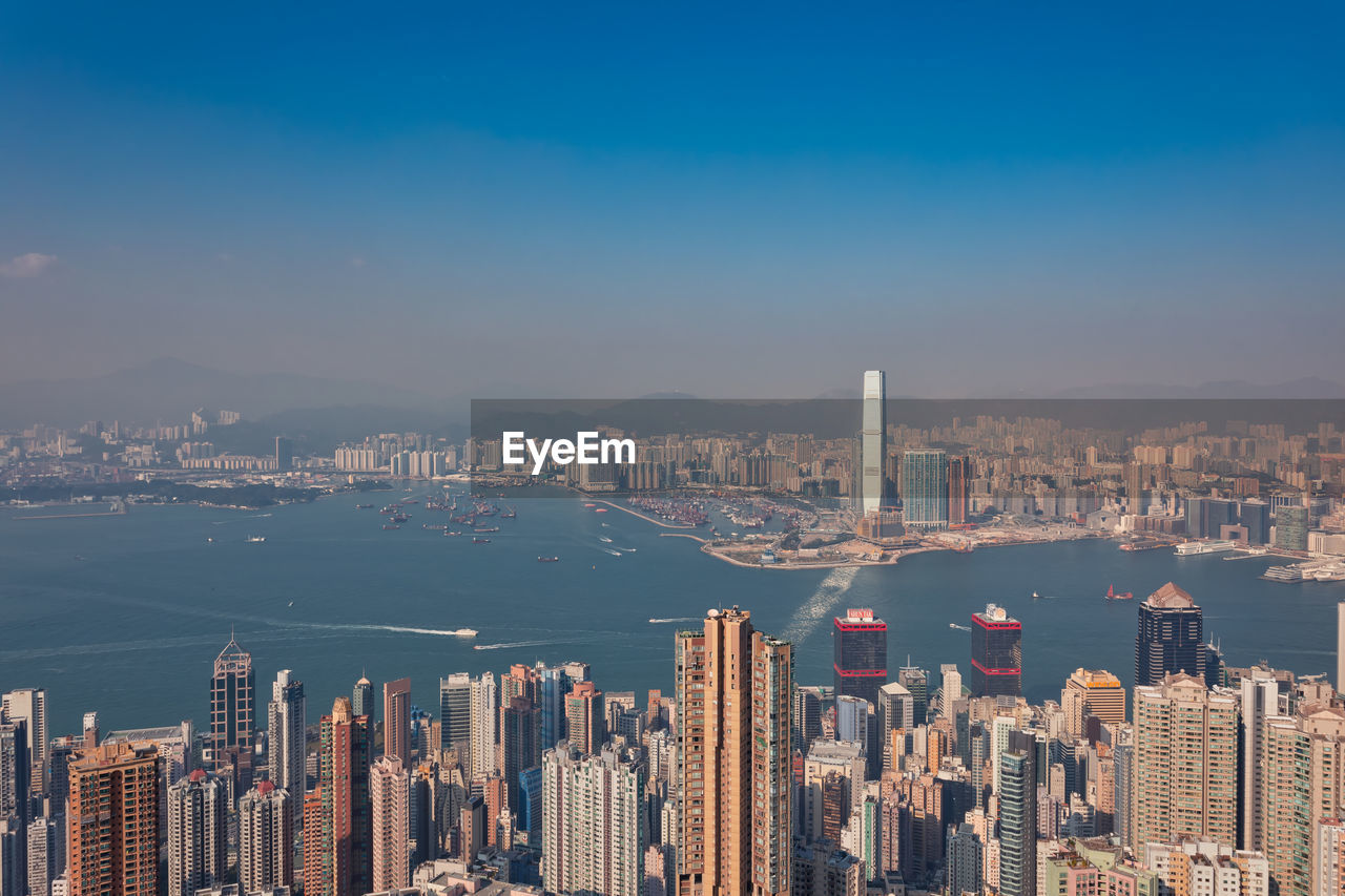 Aerial view of city by sea against sky