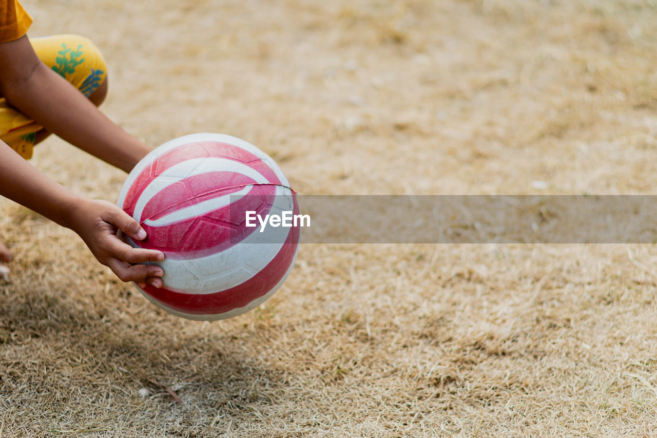 ball, sports, one person, sand, childhood, child, leisure activity, land, day, nature, soccer, beach, hand, holding, limb, lifestyles, motion, human limb, yellow, sports equipment, playground, focus on foreground, outdoors, competition, recreation, side view, women, human leg