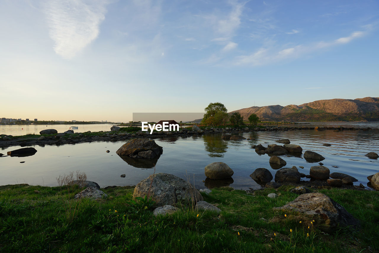 Scenic view of rocks by lake against sky