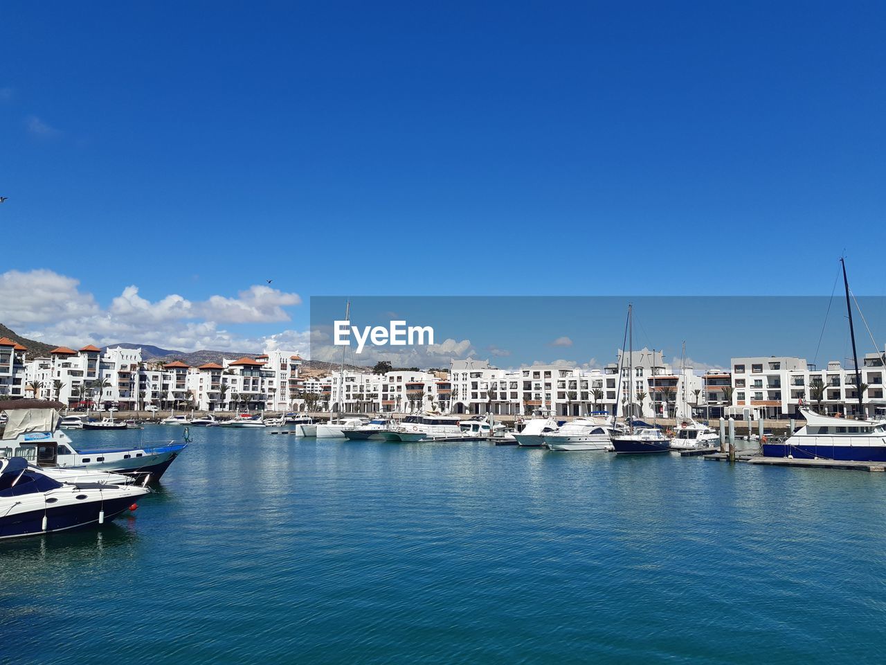 SAILBOATS MOORED AT HARBOR