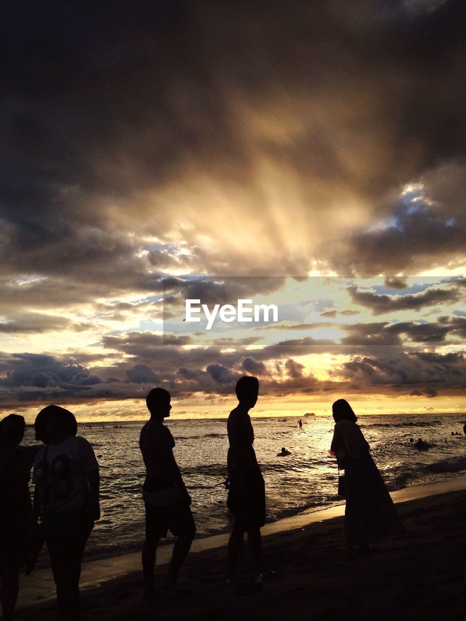 Silhouette image of friends enjoying at beach against sky during sunset