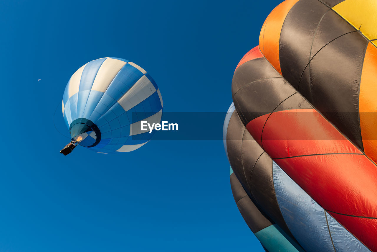 Low angle view of colorful hot air balloons flying against clear blue sky