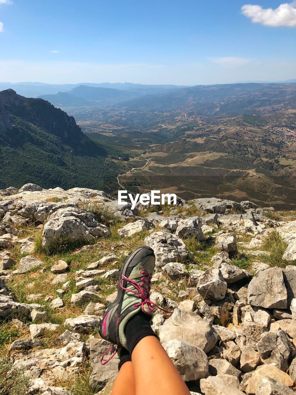 MAN STANDING ON ROCK AGAINST MOUNTAIN