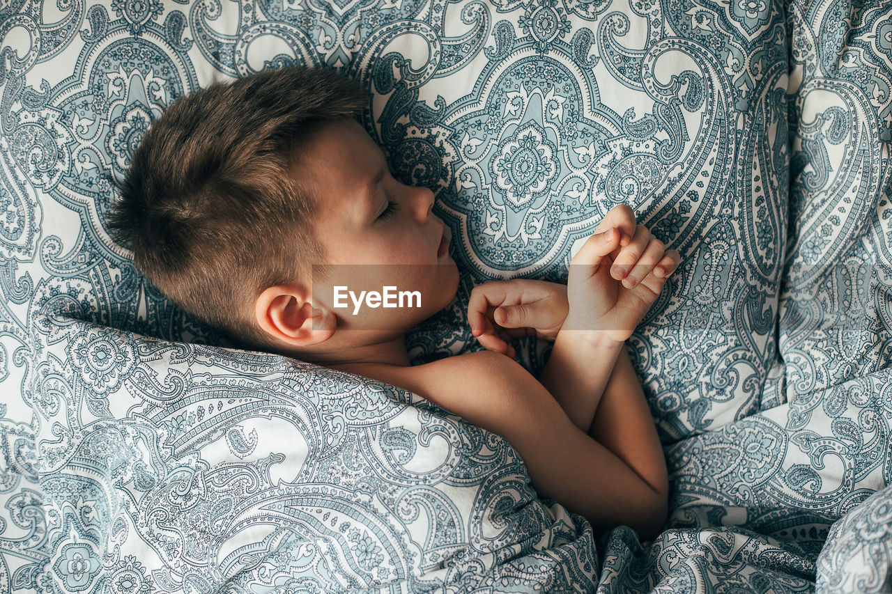 HIGH ANGLE VIEW OF WOMAN LYING IN BED