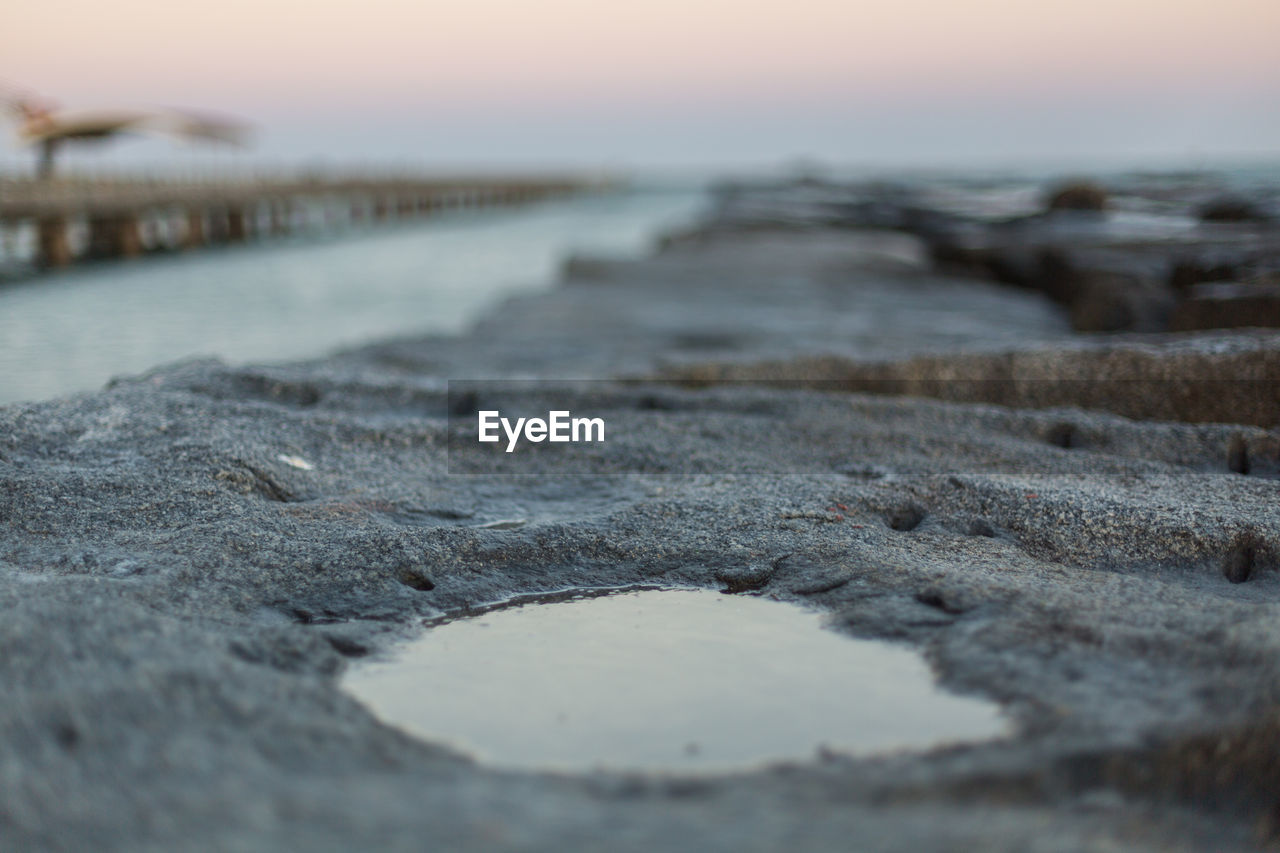 CLOSE-UP OF BEACH AGAINST SKY DURING SUNSET