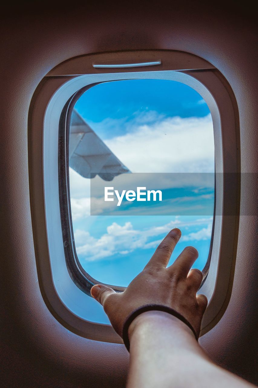 Close-up of woman hand at airplane window