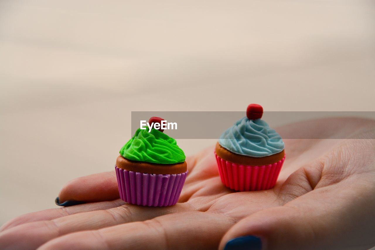 Cropped hand of woman holding small muffins