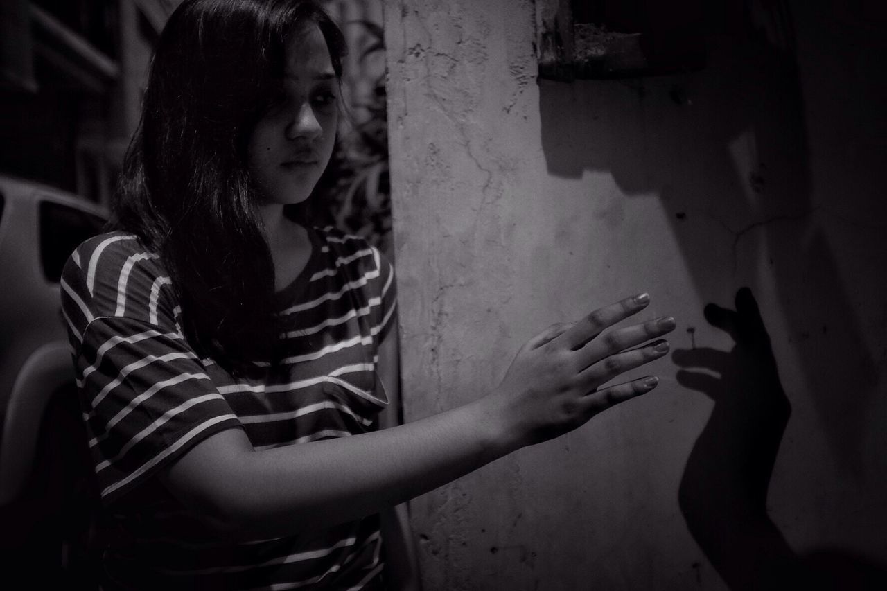 Young woman reaching her shadow on wall