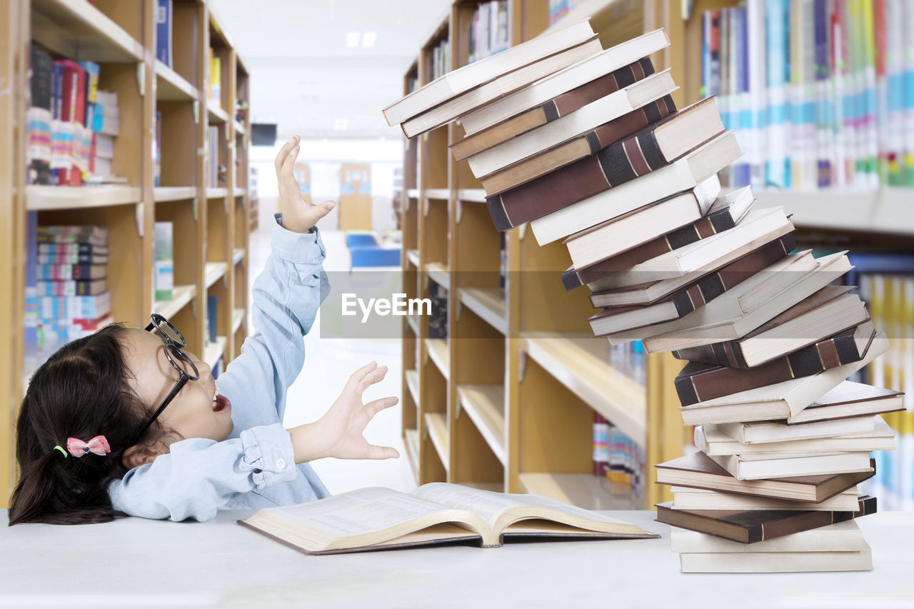 Books falling on girl in library