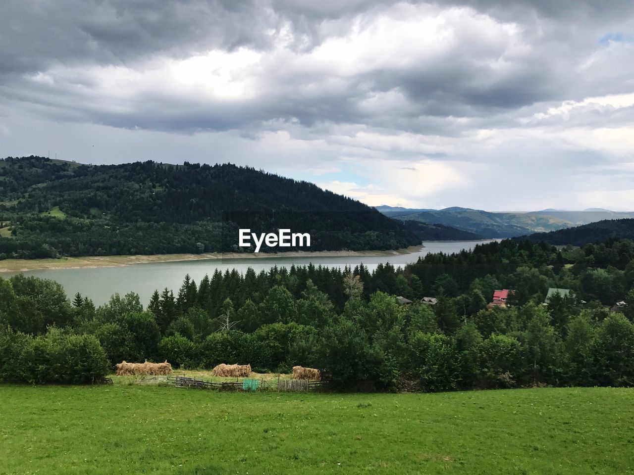 Scenic view of field by lake against sky