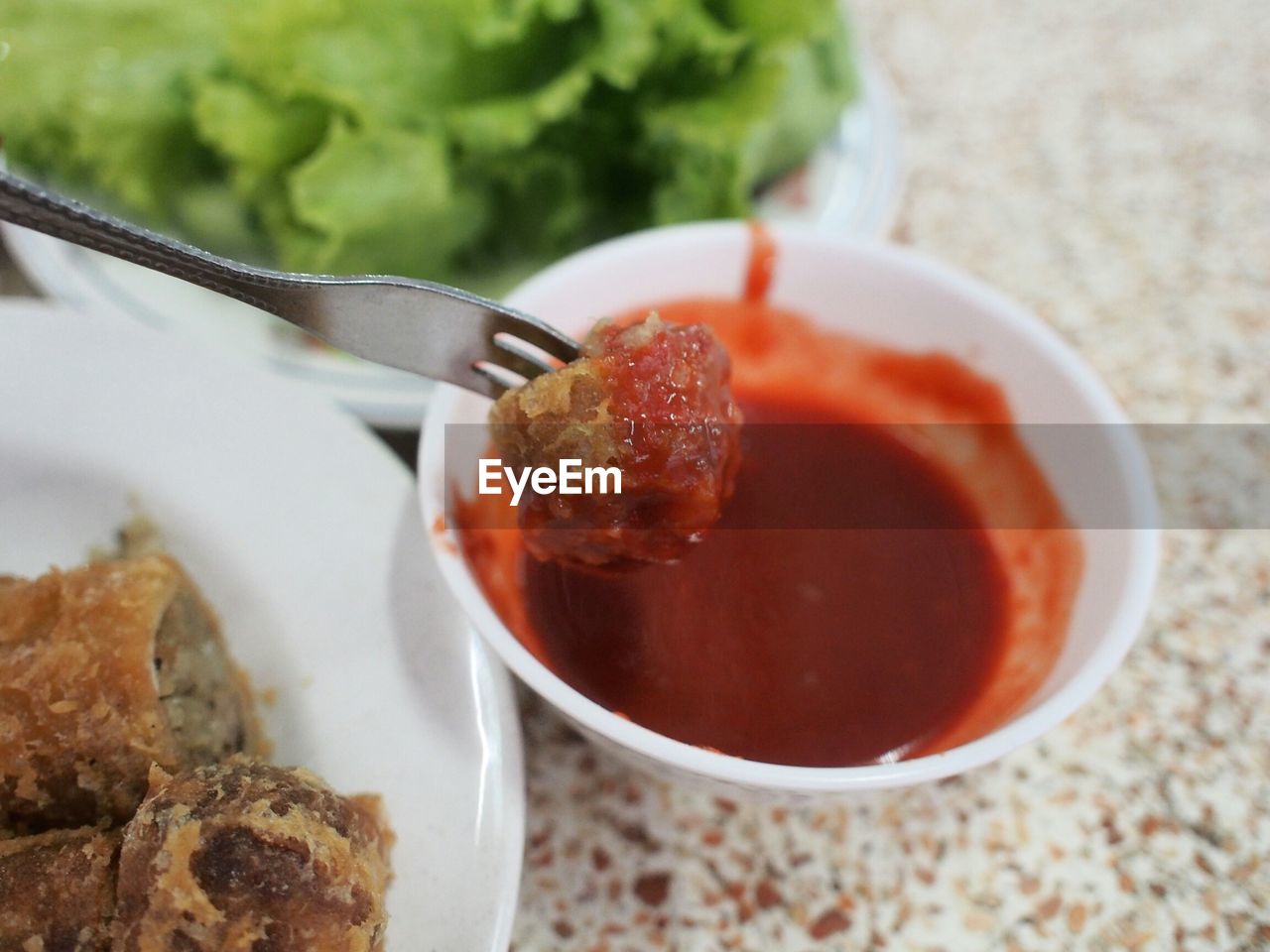 Close-up of spring roll over savory sauce on table