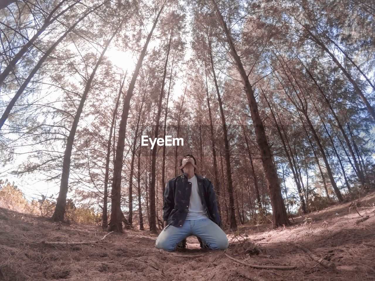 Man kneeling against trees in forest