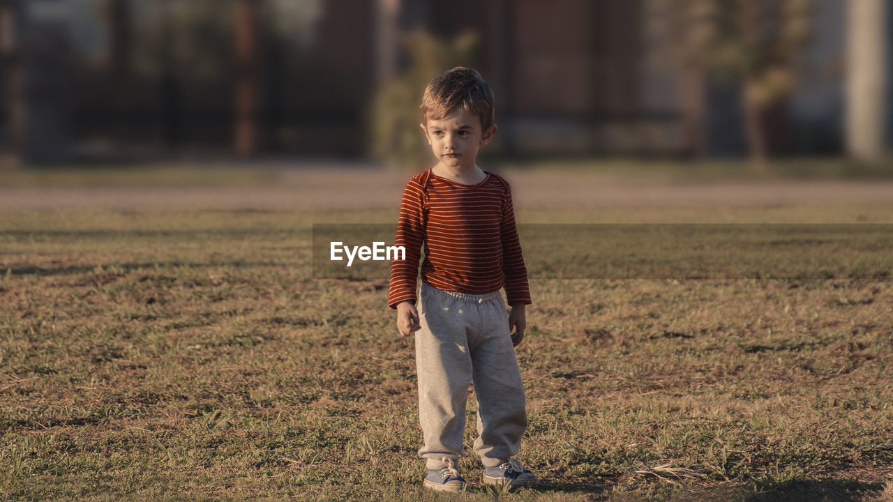 BOY STANDING IN FIELD