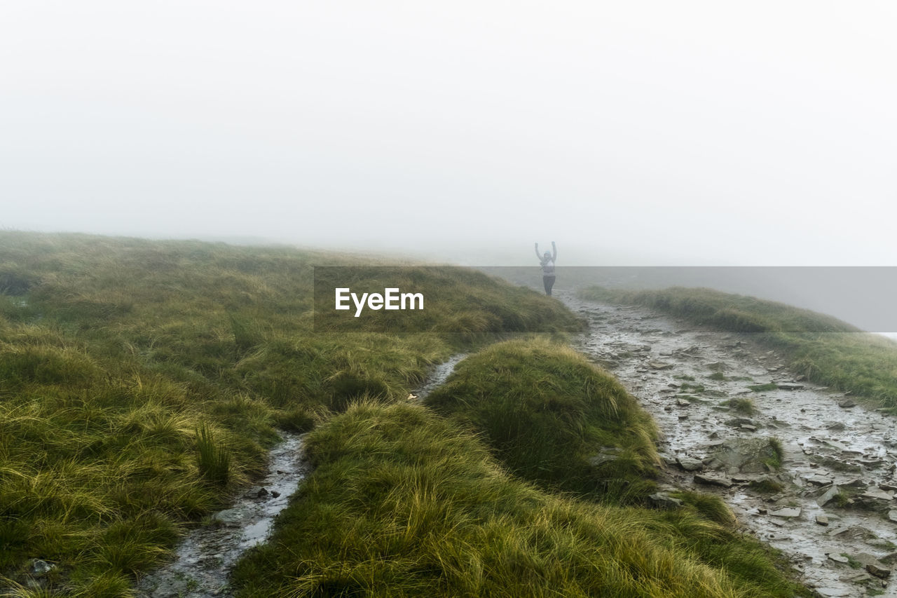 Mid distance view of person standing on grassy mountain during foggy weather at yorkshire dales