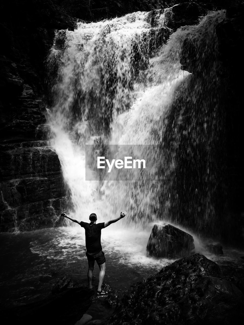 Rear view of man standing against waterfall