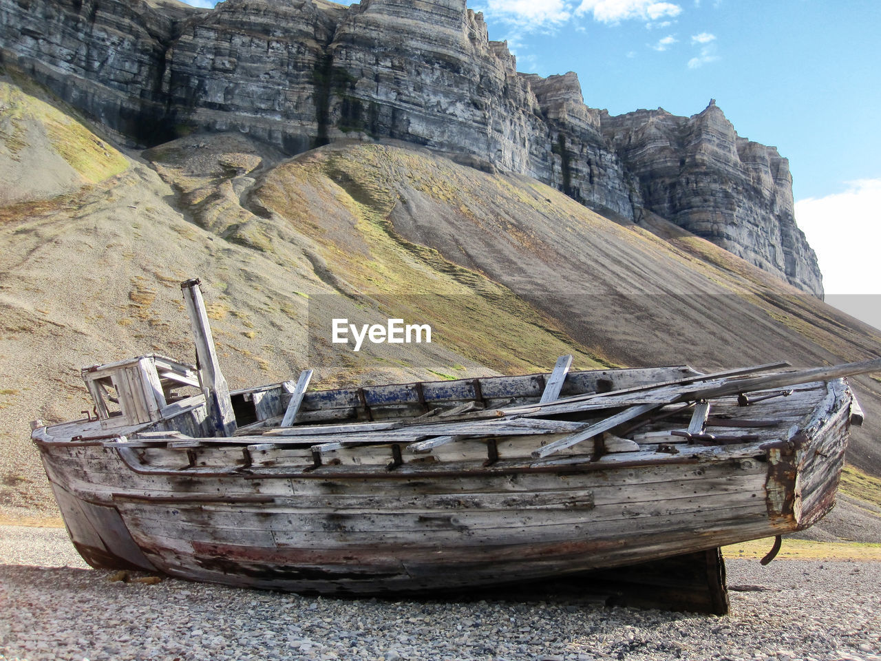 ABANDONED BOAT ON SHORE AGAINST SKY