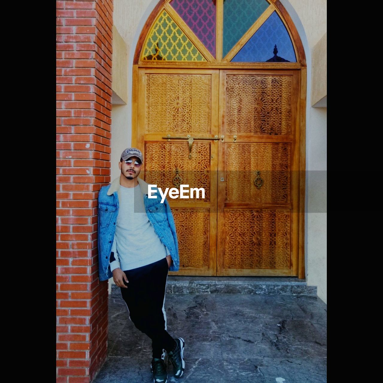 FULL LENGTH PORTRAIT OF MAN STANDING AGAINST DOOR OF BUILDING