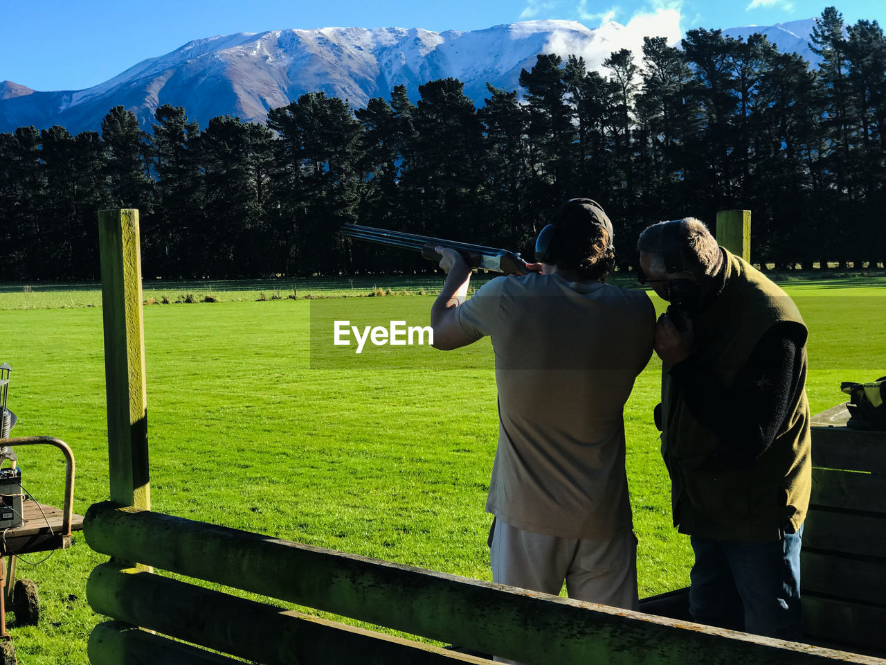 Rear view of man clay shooting against mountain