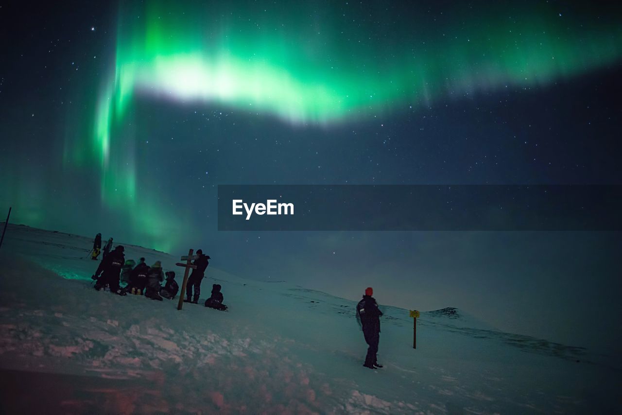 People on snowy mountain against idyllic aurora