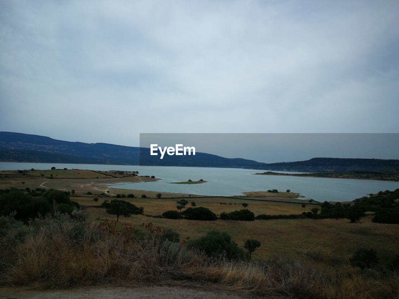 SCENIC VIEW OF LAKE BY FIELD AGAINST SKY