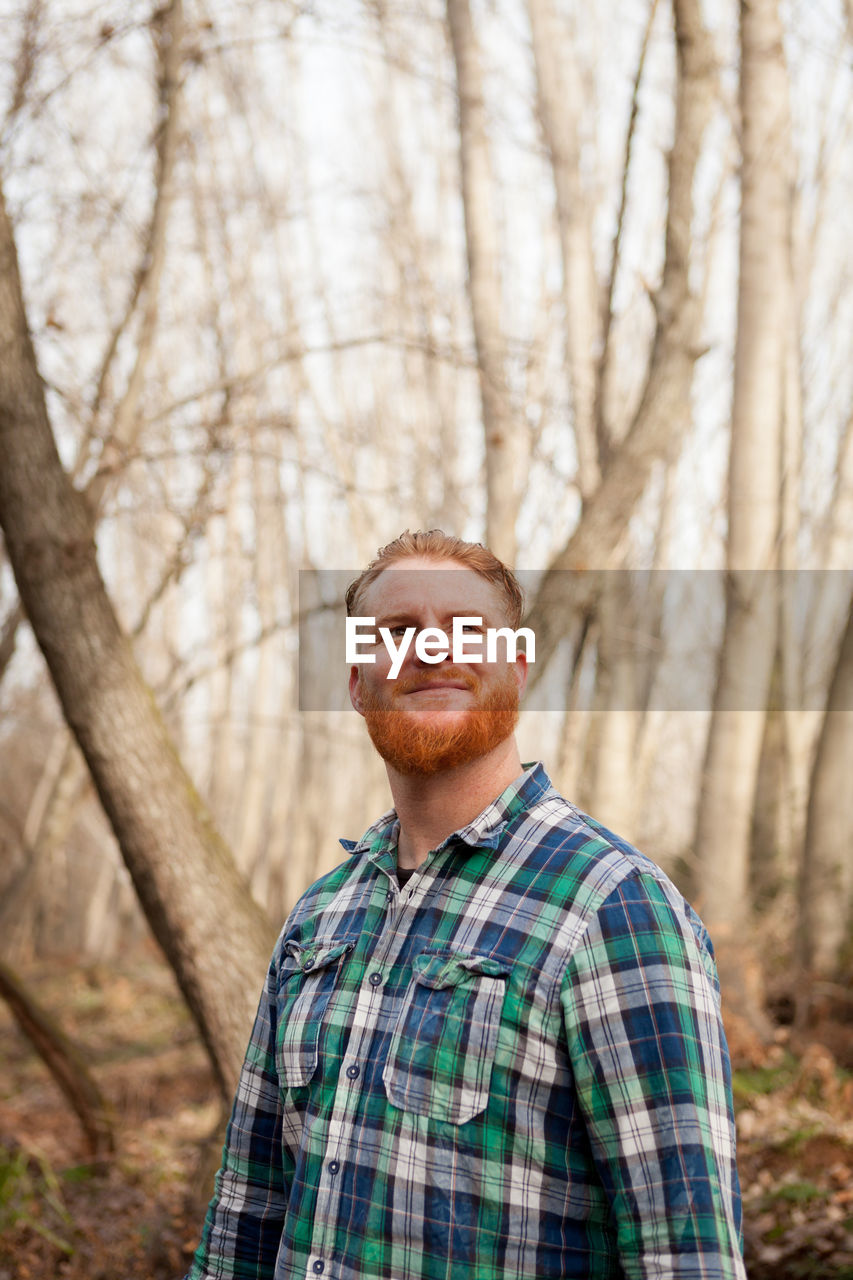 PORTRAIT OF SMILING MAN ON TREE