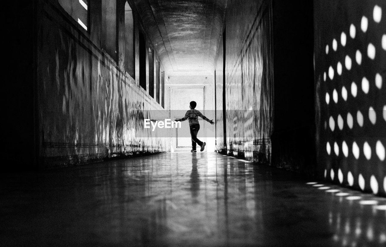 Boy running in corridor on sunny day