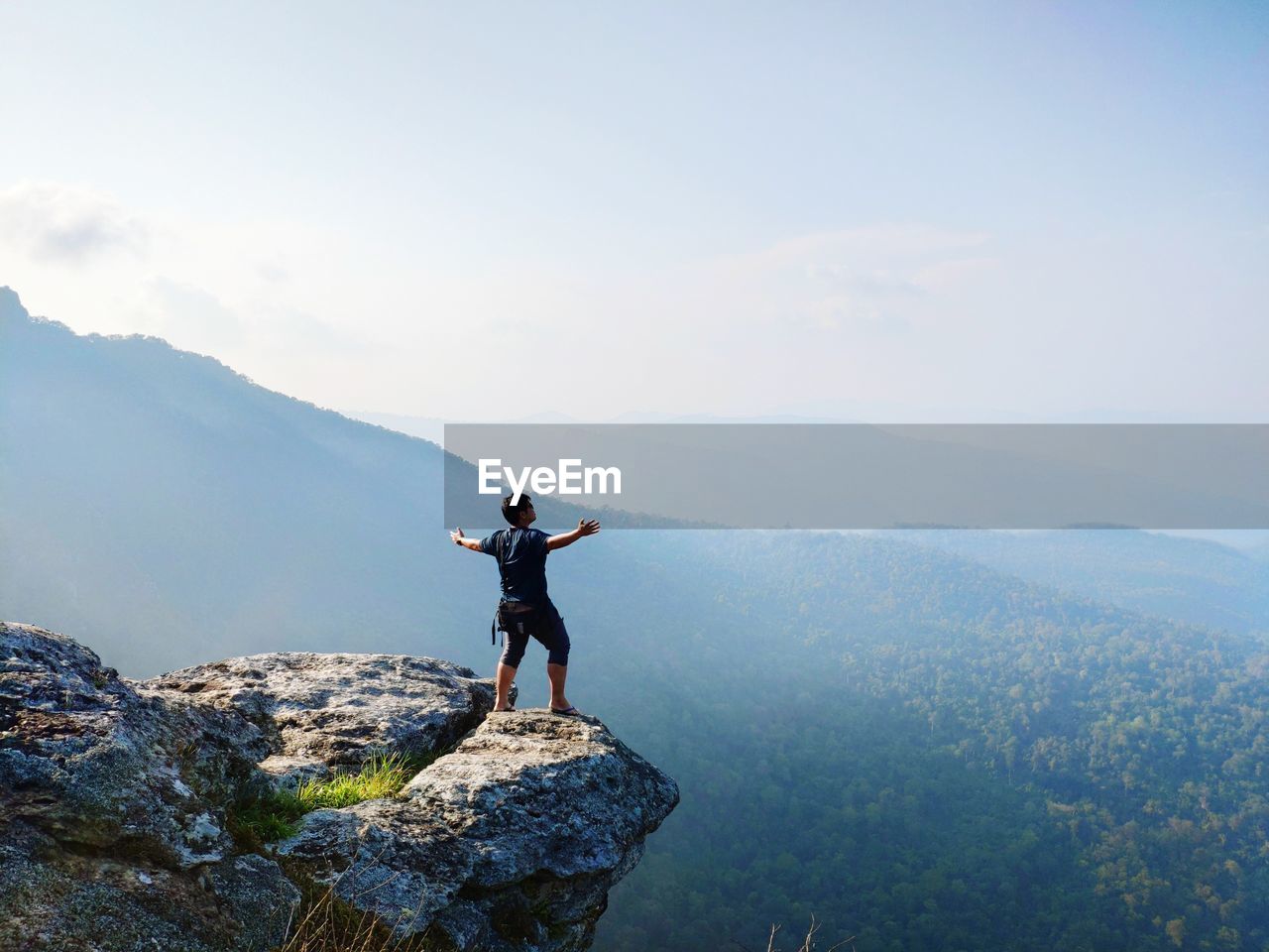 Man standing with arms outstretched at mountain against sky