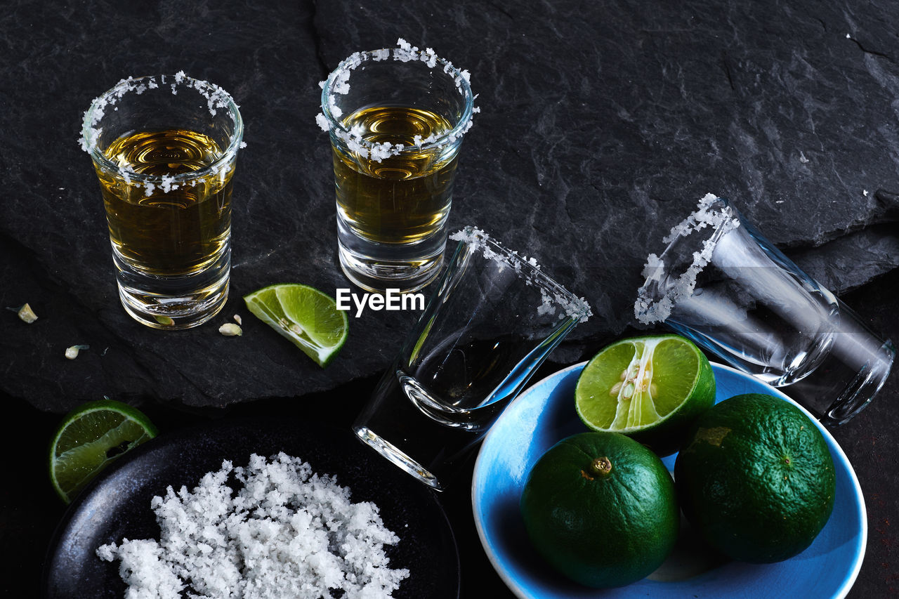 High angle view of tequila shots by lime and salt on table