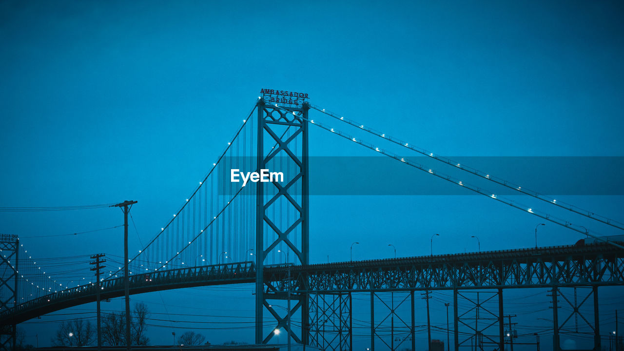 Low angle view of suspension bridge against blue sky ambassador bridge