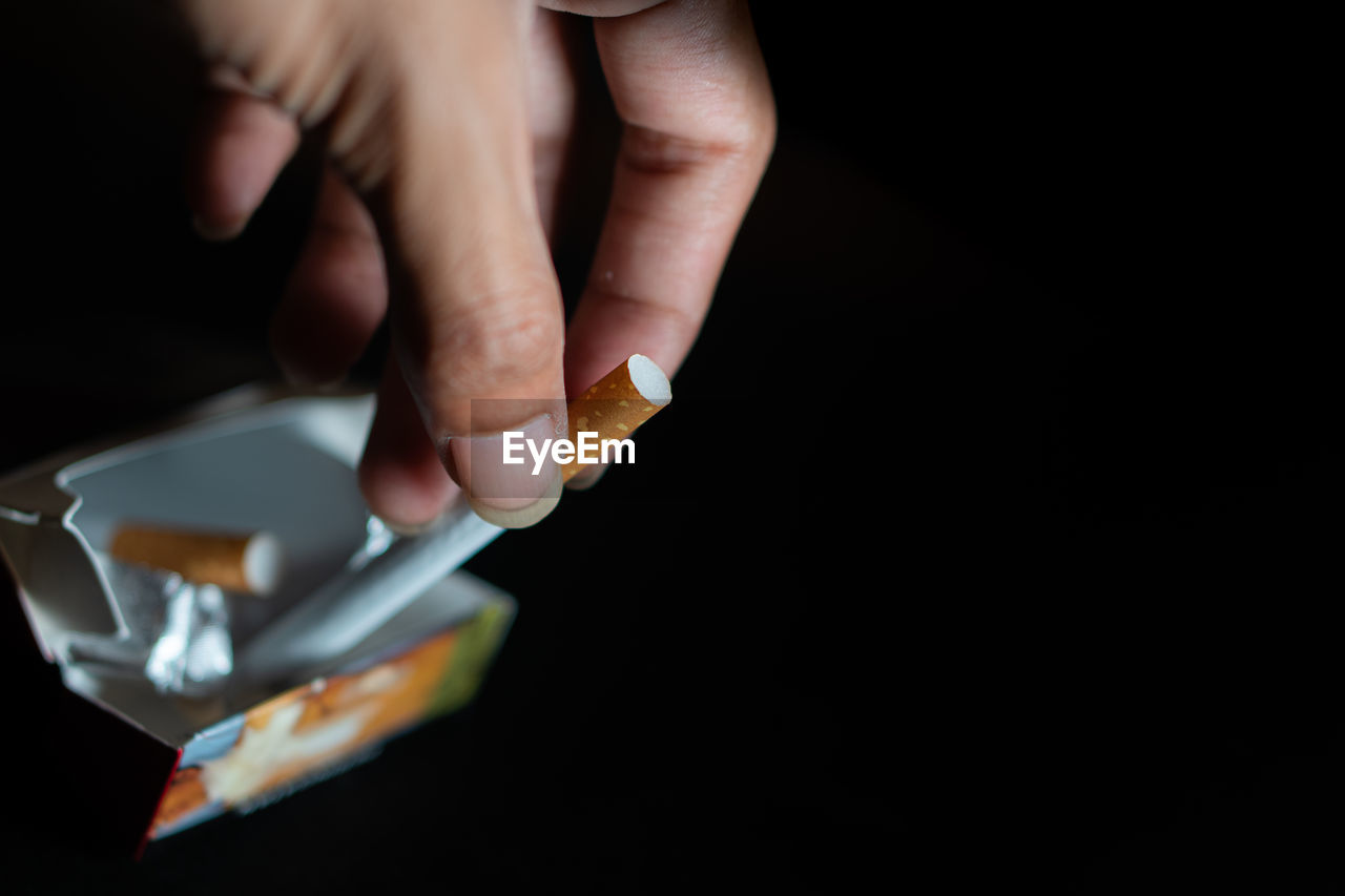 cropped hand of person holding dentures against black background