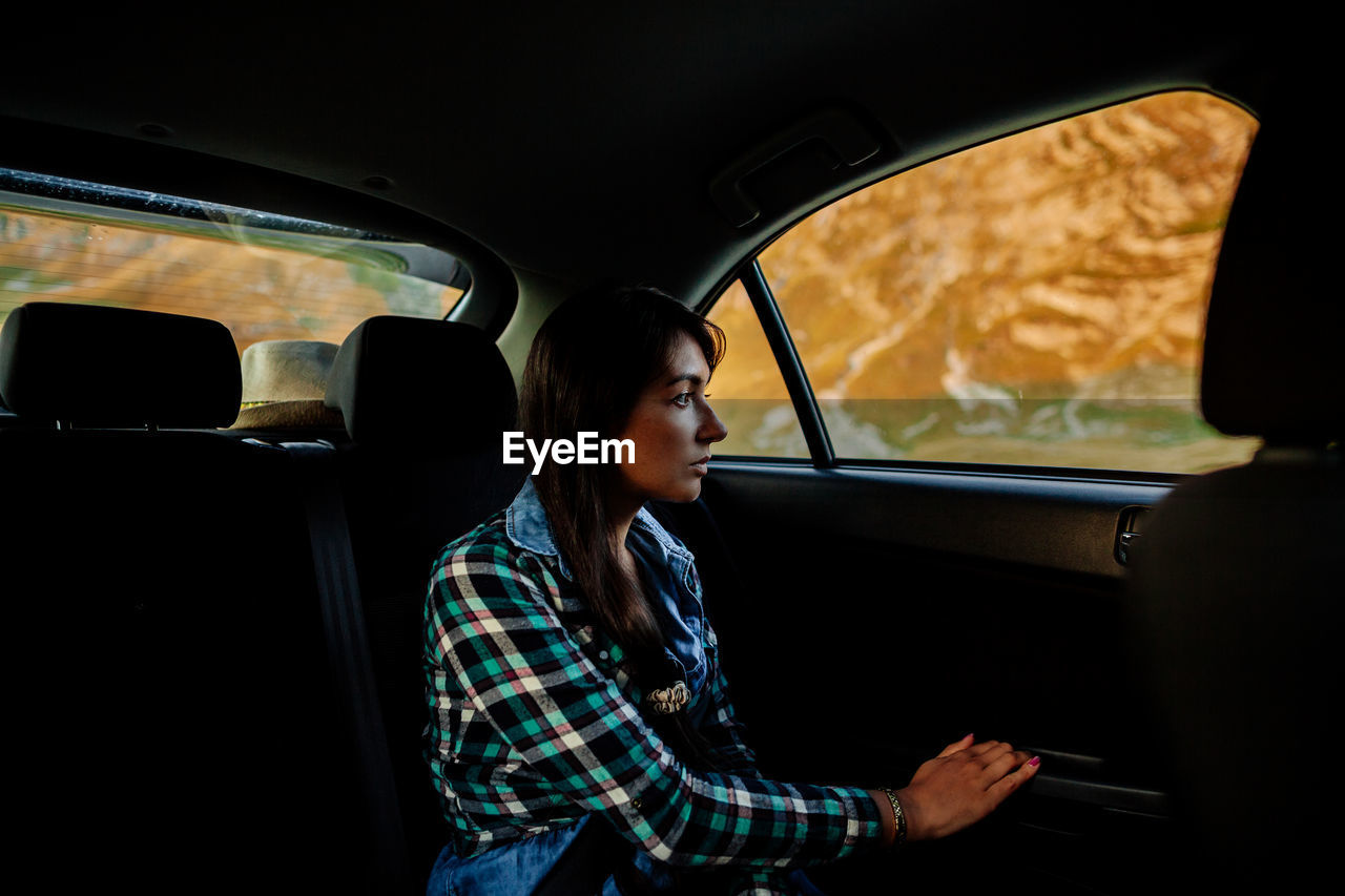 Young woman looking through car window