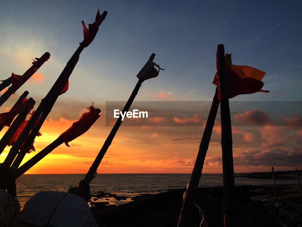 Silhouette sticks on shore during sunset