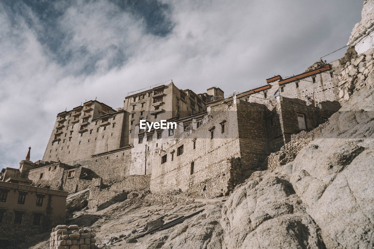 Low angle view of old buildings against cloudy sky