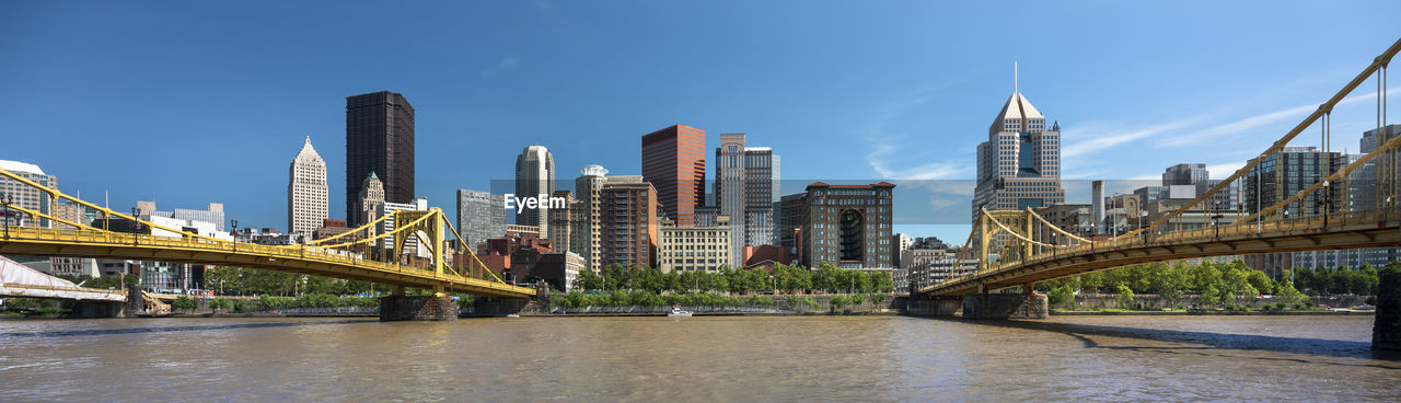 BRIDGE OVER RIVER BY BUILDINGS IN CITY AGAINST SKY