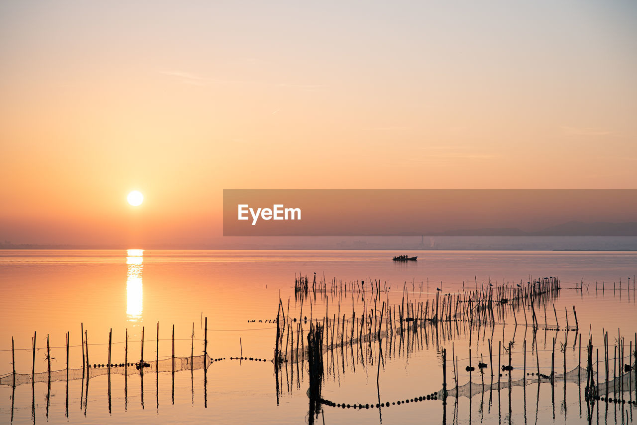 Boat and fishing nets at valencia's albufera sunset against the light