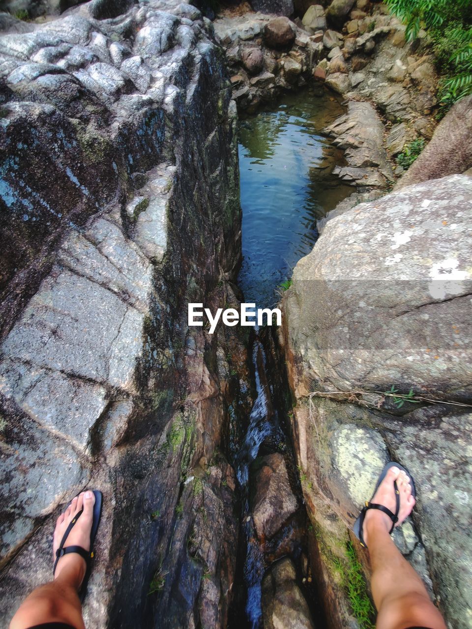 LOW SECTION OF PERSON STANDING ON ROCK AT SHORE