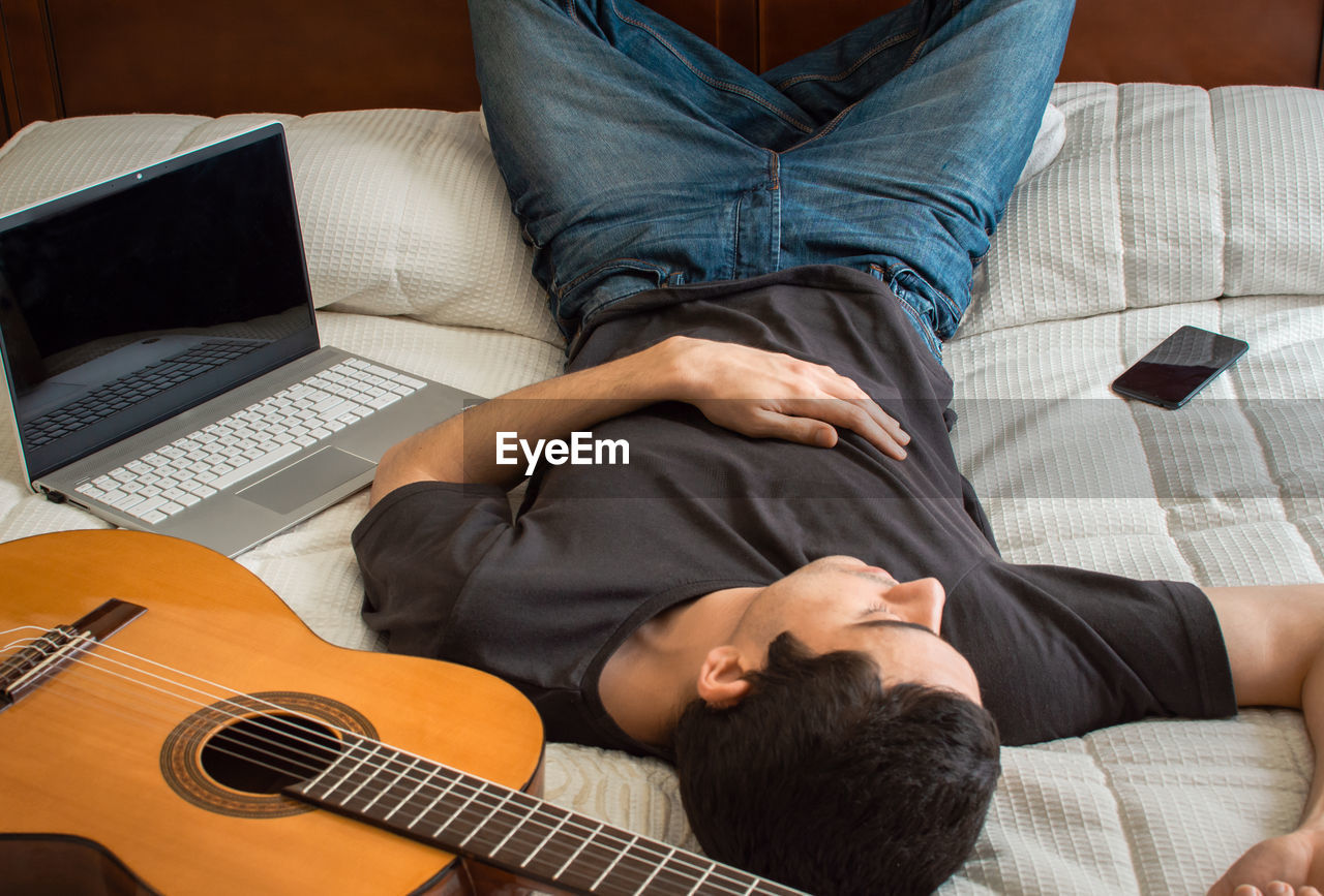 High angle view of man lying on bed at home