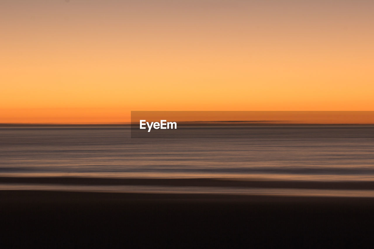 SCENIC VIEW OF SEA AGAINST CLEAR SKY DURING SUNSET