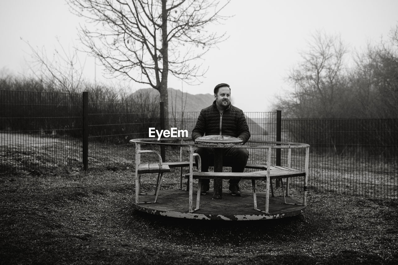 Man sitting on a carousel on a playground 