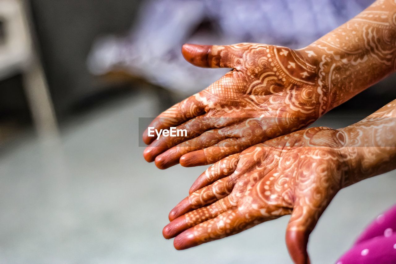 Cropped image of woman showing henna tattoo on hands