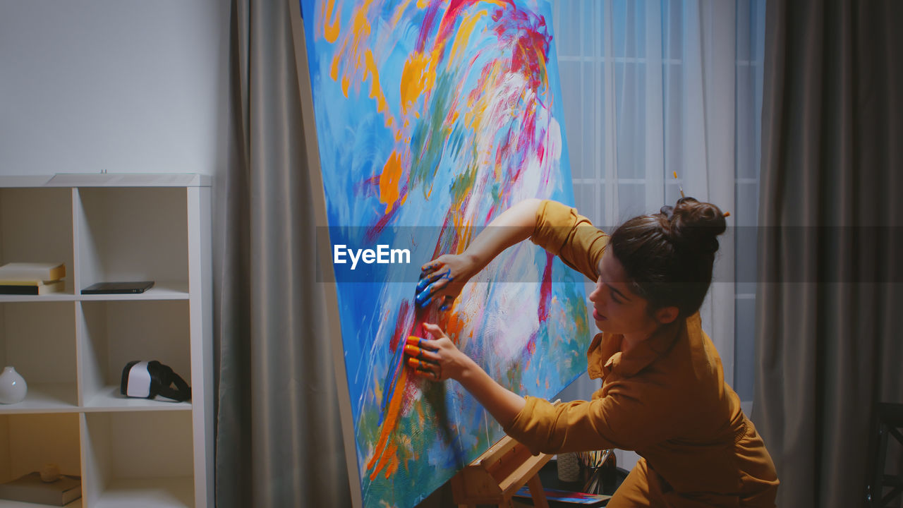 Side view of woman painting at home