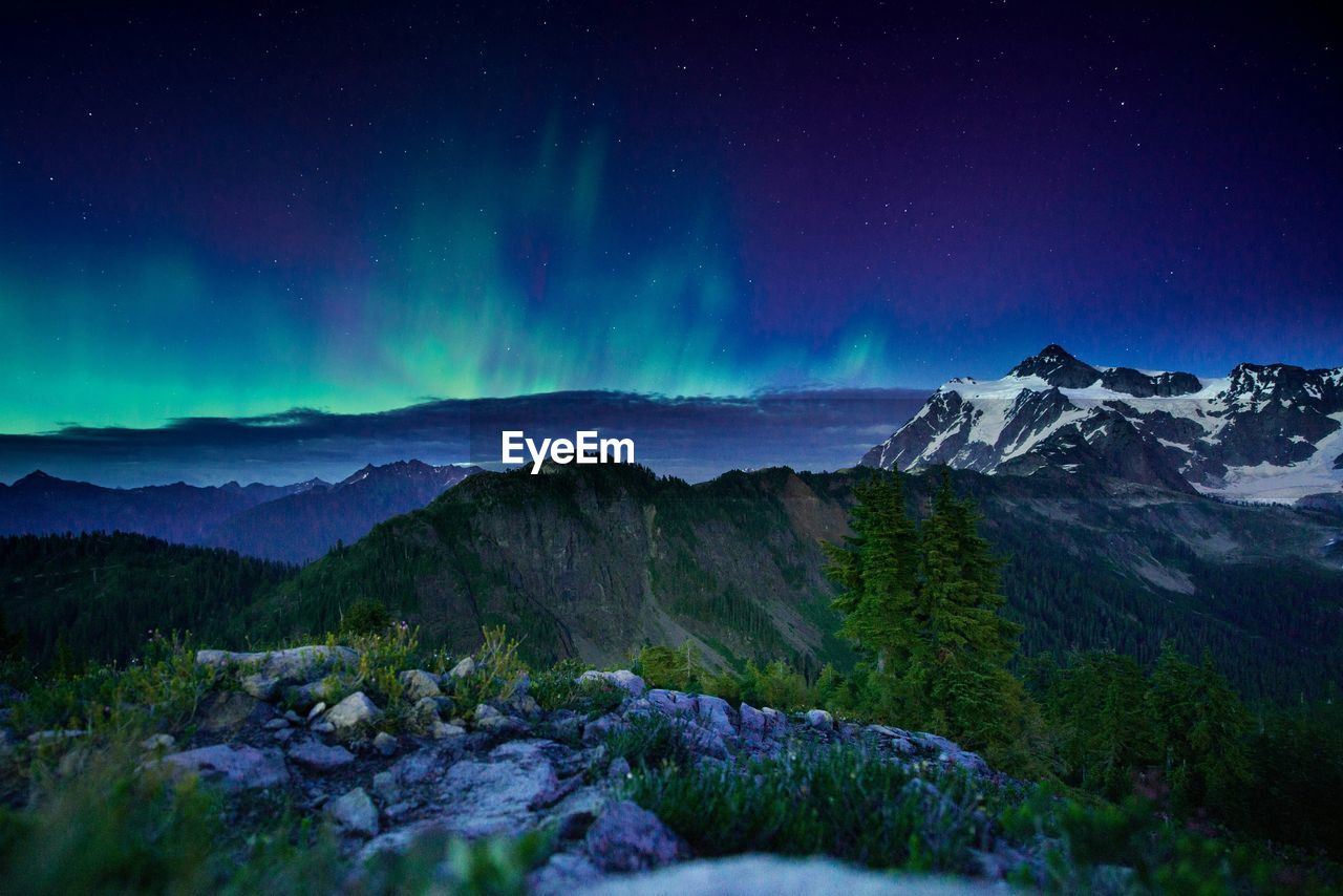 Scenic view of landscape against aura at dusk