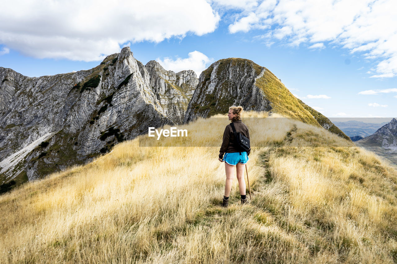 Rear view of woman walking on mountain against sky with mountain in background