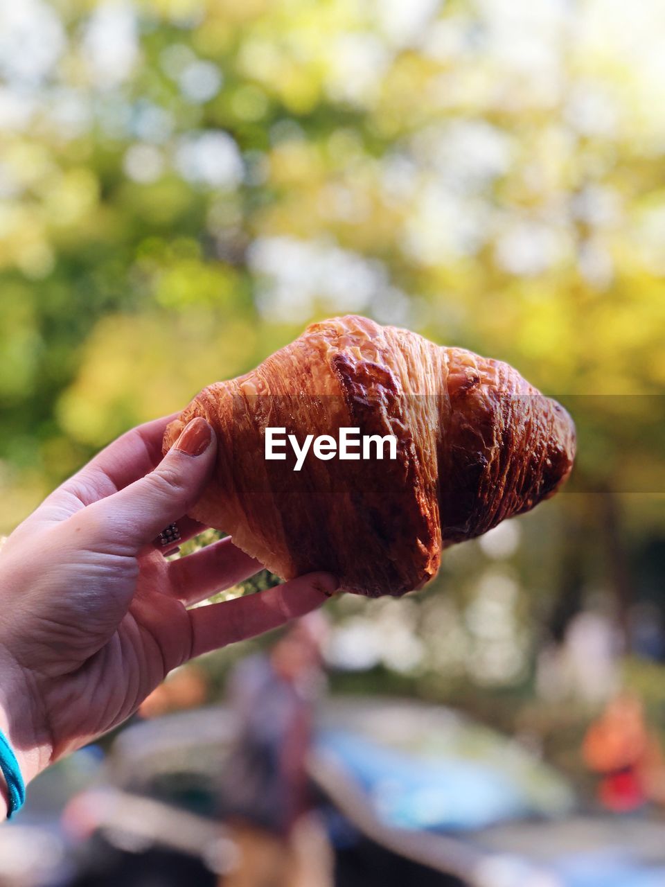 Close-up of woman hand holding croissant outdoors