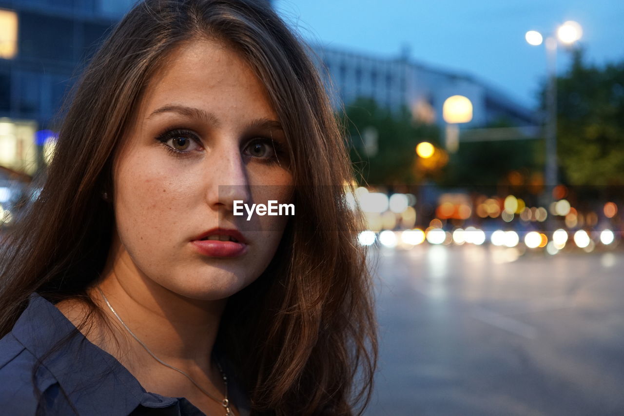 Portrait of shocked woman standing on street at dusk