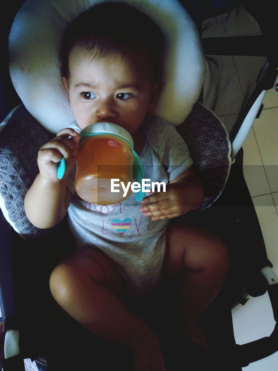 High angle view of baby boy drinking milk while sitting in stroller