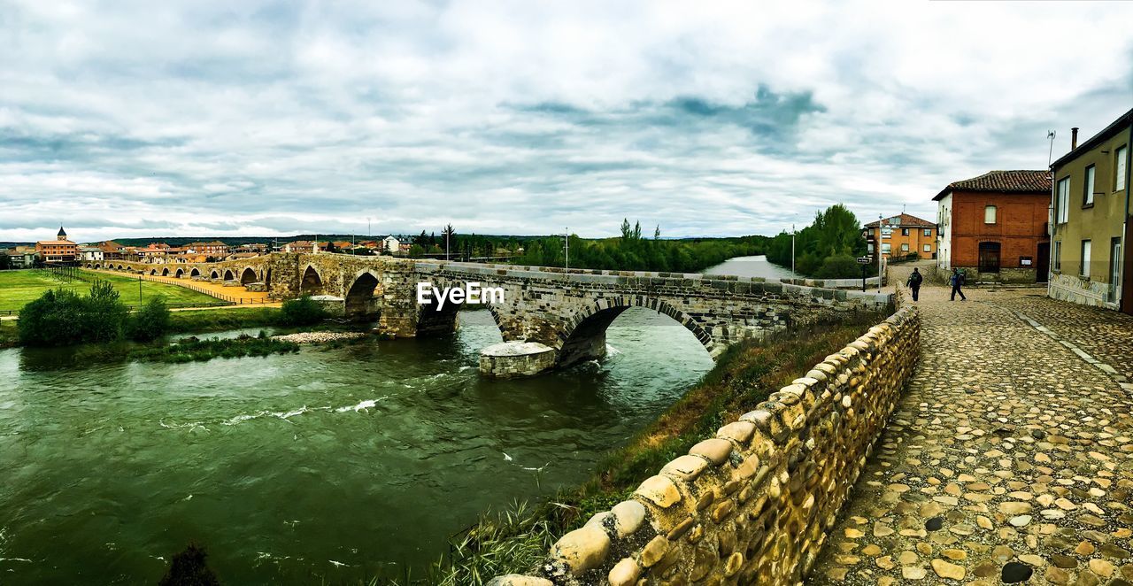 Bridge over river against cloudy sky