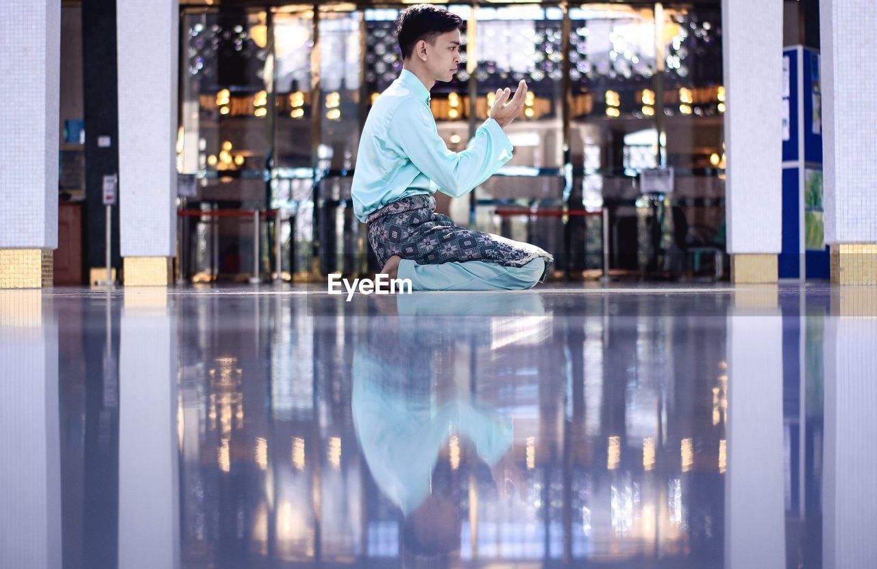 Man praying while sitting on floor